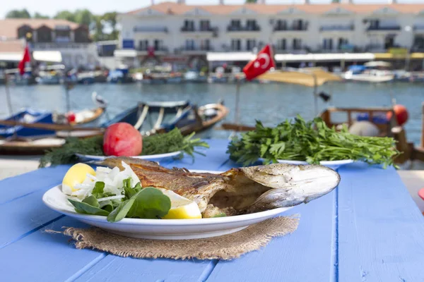 Yeşil ve mavi ahşap masa açık havada limon ile ızgara levrek balık
