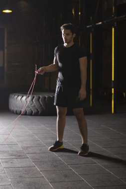 Genç atlet spor salonunda ip atlama egzersizleri yapıyor. Karanlık fotoğraf konsepti ile kopyalama alanı metin alanı.