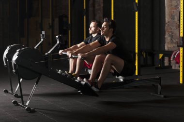 İki genç sporcuların spor salonunda egzersiz yukarı itin gerçekleştirme. Karanlık fotoğraf konsepti ile kopyalama alanı metin alanı.