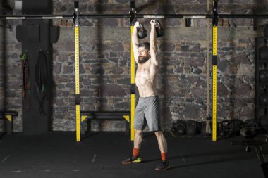 Genç sakallı ve gömleksiz atlet spor salonunda egzersiz için Ireland ile ısınıyor. Kopyalama alanı alanı konseptiyle karanlık fotoğraf. 