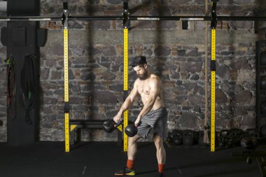 Genç sakallı ve gömleksiz atlet spor salonunda egzersiz için Ireland ile ısınıyor. Kopyalama alanı alanı konseptiyle karanlık fotoğraf. 