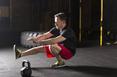 Tabanca pratik atlet spor salonunda squats. Karanlık fotoğraf konsepti ile kopyalama alanı metin alanı.