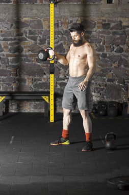 Genç sakallı ve gömleksiz atlet spor salonunda egzersiz için Ireland ile ısınıyor. Kopyalama alanı alanı konseptiyle karanlık fotoğraf. 