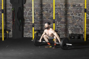 Ağır bir halter salonunda ile eğitim genç sakallı ve gömleksiz atlet. Kopyalama alanı alanı konseptiyle karanlık fotoğraf.