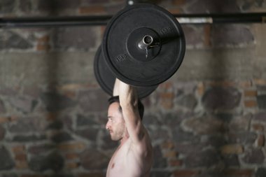 Tuğla duvar arka plan ile spor salonunda Olimpiyat asansörleri pratik üstsüz Erkek atlet.