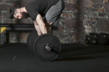 Genç atlet ile ağır bir halter salonunda eğitim sakallı. Kopyalama alanı alanı konseptiyle karanlık fotoğraf.