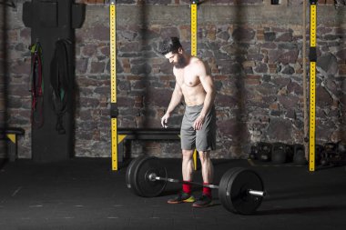 Ağır bir halter salonunda ile eğitim genç sakallı ve gömleksiz atlet. Kopyalama alanı alanı konseptiyle karanlık fotoğraf.