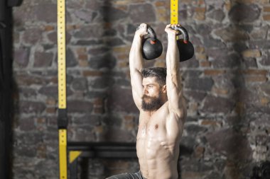 Genç sakallı ve gömleksiz atlet spor salonunda egzersiz için Ireland ile ısınıyor. Kopyalama alanı alanı konseptiyle karanlık fotoğraf. 