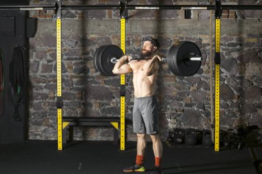 Ağır bir halter salonunda ile eğitim genç sakallı ve gömleksiz atlet. Kopyalama alanı alanı konseptiyle karanlık fotoğraf.