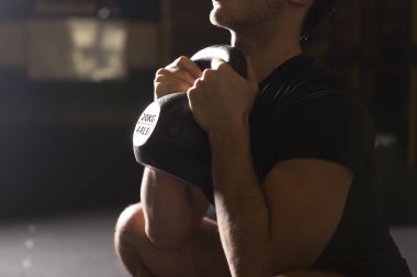 Genç Erkek atlet kadehi pratik Ireland ile spor salonunda squats. Karanlık fotoğraf konsepti ile kopyalama alanı metin alanı.