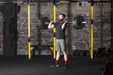 Genç atlet ile ağır bir halter salonunda eğitim sakallı. Kopyalama alanı alanı konseptiyle karanlık fotoğraf.