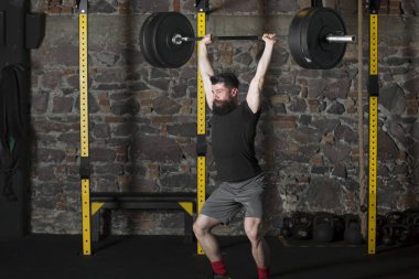 Genç atlet ile ağır bir halter salonunda eğitim sakallı. Kopyalama alanı alanı konseptiyle karanlık fotoğraf.