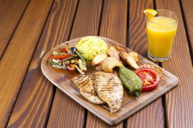Grilled chicken breast with fresh vegetables and potato paste and orange juice on wood table background.  clipart