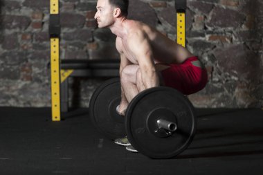 Tuğla duvar arka plan ile spor salonunda Olimpiyat asansörleri pratik üstsüz Erkek atlet.