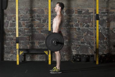 Tuğla duvar arka plan ile spor salonunda Olimpiyat asansörleri pratik üstsüz Erkek atlet.