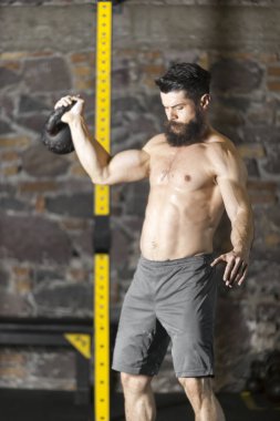 Genç sakallı ve gömleksiz atlet spor salonunda egzersiz için Ireland ile ısınıyor. Kopyalama alanı alanı konseptiyle karanlık fotoğraf. 