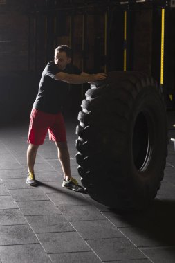 Siyah gömlek adam büyük ağır lastik spor salonunda saygısız.