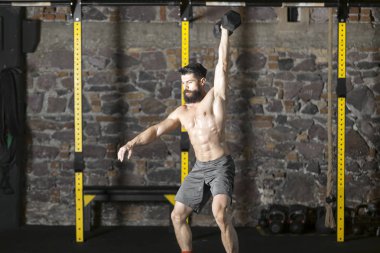 Genç sakallı ve halter pratik gömleksiz atlet spor salonunda kaçırır. Kopyalama alanı alanı konseptiyle karanlık fotoğraf. 