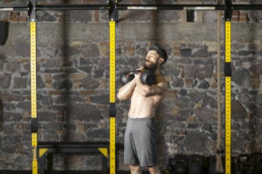 Genç sakallı ve gömleksiz atlet spor salonunda egzersiz için Ireland ile ısınıyor. Kopyalama alanı alanı konseptiyle karanlık fotoğraf. 