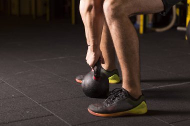 Kettlebell pratik genç atlet spor salonunda sallanır. Karanlık fotoğraf kavramı kopya alanı ile.