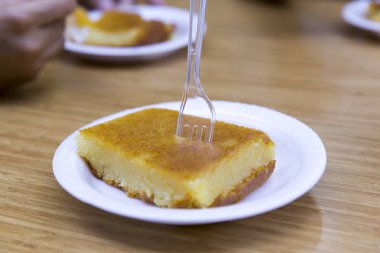 Türk ve Yunan geleneksel ramazan tatlı peynirli helva beyaz plaka ve ahşap masa arka plan üzerinde plastik çatal ile hizmet veren pasta (Peynir Helvasi). Kopya alanı. 