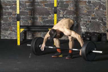Ağır bir halter salonunda ile eğitim genç sakallı ve gömleksiz atlet. Kopyalama alanı alanı konseptiyle karanlık fotoğraf.