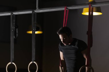 Çekici bir genç adam çekme işi ups tuğla duvarlı eğitim salonunda açık bar. Karanlık fotoğraf konsepti ile kopyalama alanı metin alanı.