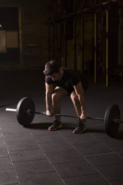 Ağır bir halter salonunda ile eğitim genç atlet. Kopyalama alanı alanı konseptiyle karanlık fotoğraf.