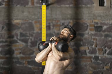 Genç sakallı ve gömleksiz atlet spor salonunda egzersiz için Ireland ile ısınıyor. Kopyalama alanı alanı konseptiyle karanlık fotoğraf. 