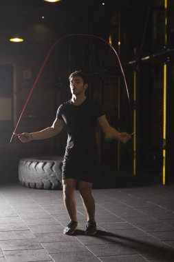 Genç atlet spor salonunda ip atlama egzersizleri yapıyor. Karanlık fotoğraf konsepti ile kopyalama alanı metin alanı.