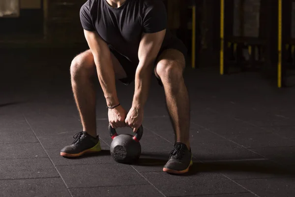 Kettlebell pratik genç atlet spor salonunda sallanır. Karanlık fotoğraf kavramı kopya alanı ile.