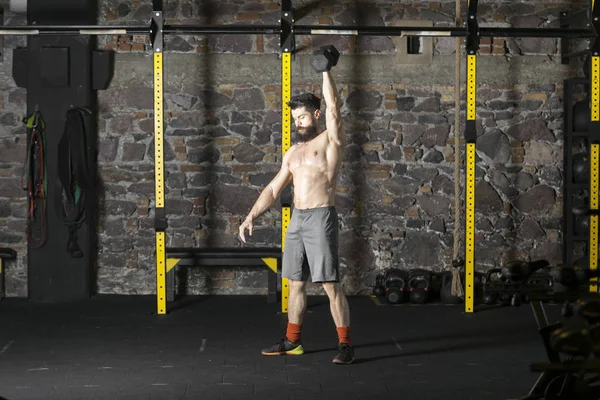 Genç sakallı ve halter pratik gömleksiz atlet spor salonunda kaçırır. Kopyalama alanı alanı konseptiyle karanlık fotoğraf. 