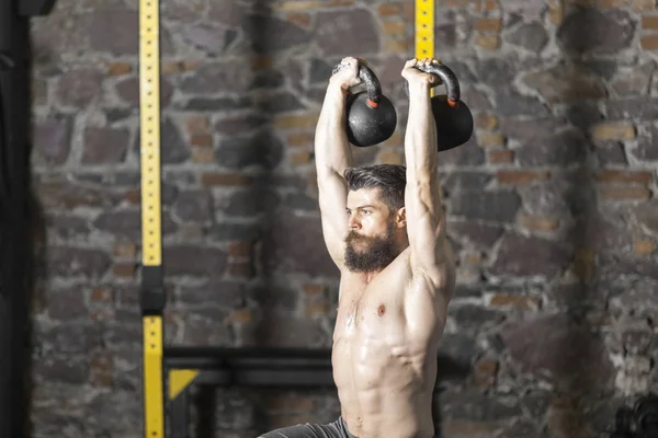 Genç sakallı ve gömleksiz atlet spor salonunda egzersiz için Ireland ile ısınıyor. Kopyalama alanı alanı konseptiyle karanlık fotoğraf. 