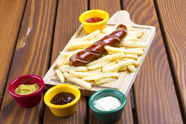Grilled pork frankfurter sausage with french fries, chips and dip sauces.