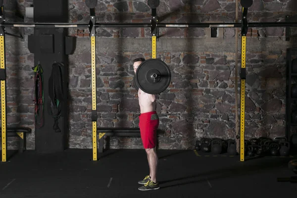 赤裸上身的男运动员在有砖墙背景的健身房练习奥运电梯 — 图库照片