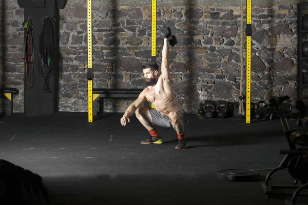 Genç sakallı ve halter pratik gömleksiz atlet spor salonunda kaçırır. Kopyalama alanı alanı konseptiyle karanlık fotoğraf. 