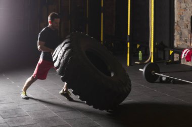 Siyah gömlek adam büyük ağır lastik spor salonunda saygısız.