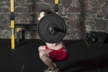 Tuğla duvar arka plan ile spor salonunda Olimpiyat asansörleri pratik üstsüz Erkek atlet.