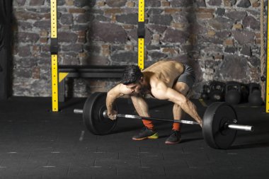 Ağır bir halter salonunda ile eğitim genç sakallı ve gömleksiz atlet. Kopyalama alanı alanı konseptiyle karanlık fotoğraf.