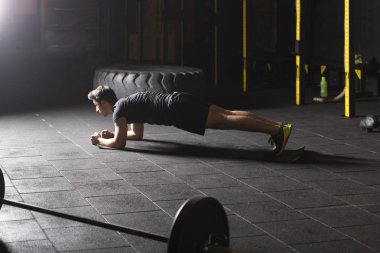 Plank. Spor salonunda egzersiz yaparken siyah spor giyim ve iş tahta pozisyonu giyen emin kaslı genç adam.