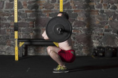 Tuğla duvar arka plan ile spor salonunda Olimpiyat asansörleri pratik üstsüz Erkek atlet.