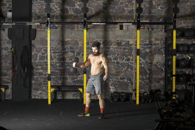 Genç sakallı ve halter pratik gömleksiz atlet spor salonunda kaçırır. Kopyalama alanı alanı konseptiyle karanlık fotoğraf. 