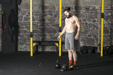 Genç sakallı ve gömleksiz atlet spor salonunda egzersiz için Ireland ile ısınıyor. Kopyalama alanı alanı konseptiyle karanlık fotoğraf. 