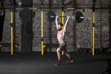 Ağır bir halter salonunda ile eğitim genç sakallı ve gömleksiz atlet. Kopyalama alanı alanı konseptiyle karanlık fotoğraf.