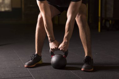 Kettlebell pratik genç atlet spor salonunda sallanır. Karanlık fotoğraf kavramı kopya alanı ile.