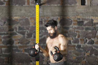 Genç sakallı ve gömleksiz atlet spor salonunda egzersiz için Ireland ile ısınıyor. Kopyalama alanı alanı konseptiyle karanlık fotoğraf. 