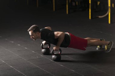 Push up kettlebells salonunda üzerinde egzersiz atlet. Karanlık fotoğraf kavramı kopya alanı ile.