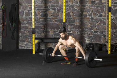 Ağır bir halter salonunda ile eğitim genç sakallı ve gömleksiz atlet. Kopyalama alanı alanı konseptiyle karanlık fotoğraf.