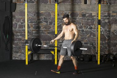 Ağır bir halter salonunda ile eğitim genç sakallı ve gömleksiz atlet. Kopyalama alanı alanı konseptiyle karanlık fotoğraf.