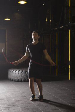 Genç atlet spor salonunda ip atlama egzersizleri yapıyor. Karanlık fotoğraf konsepti ile kopyalama alanı metin alanı.